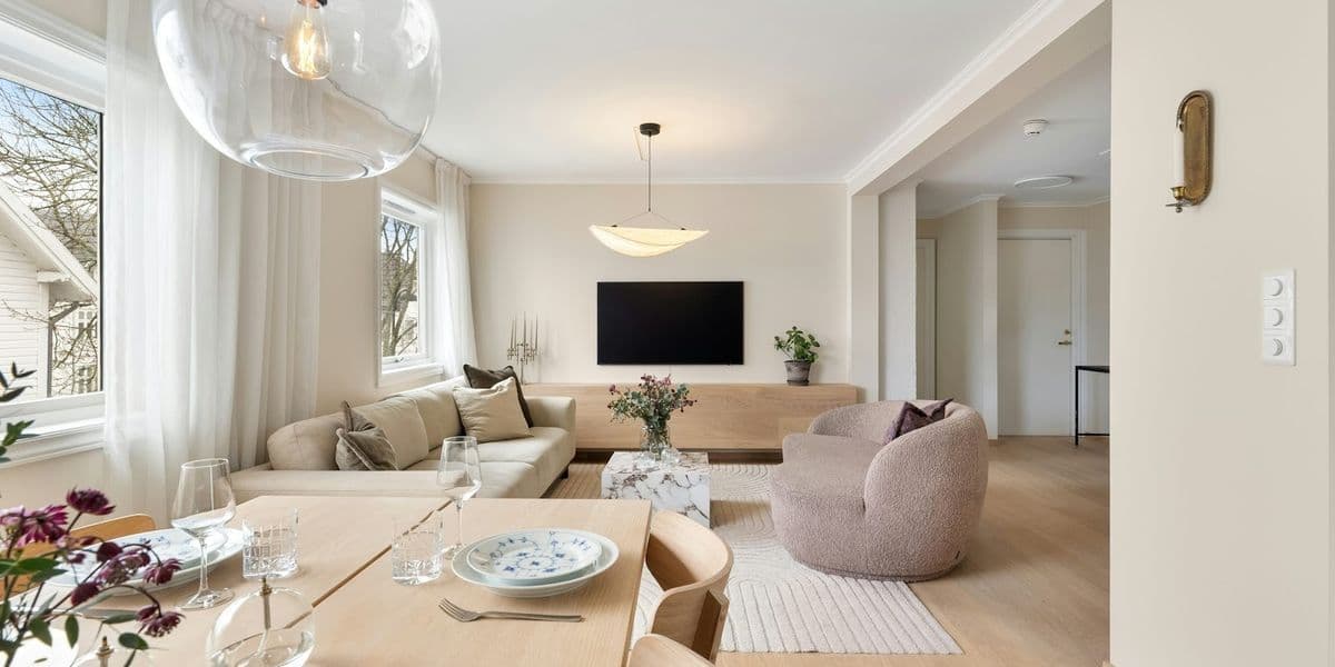 Living modern cu design interior minimalist, mobilier din lemn deschis, canapea crem și zonă de dining într-un spațiu luminos.