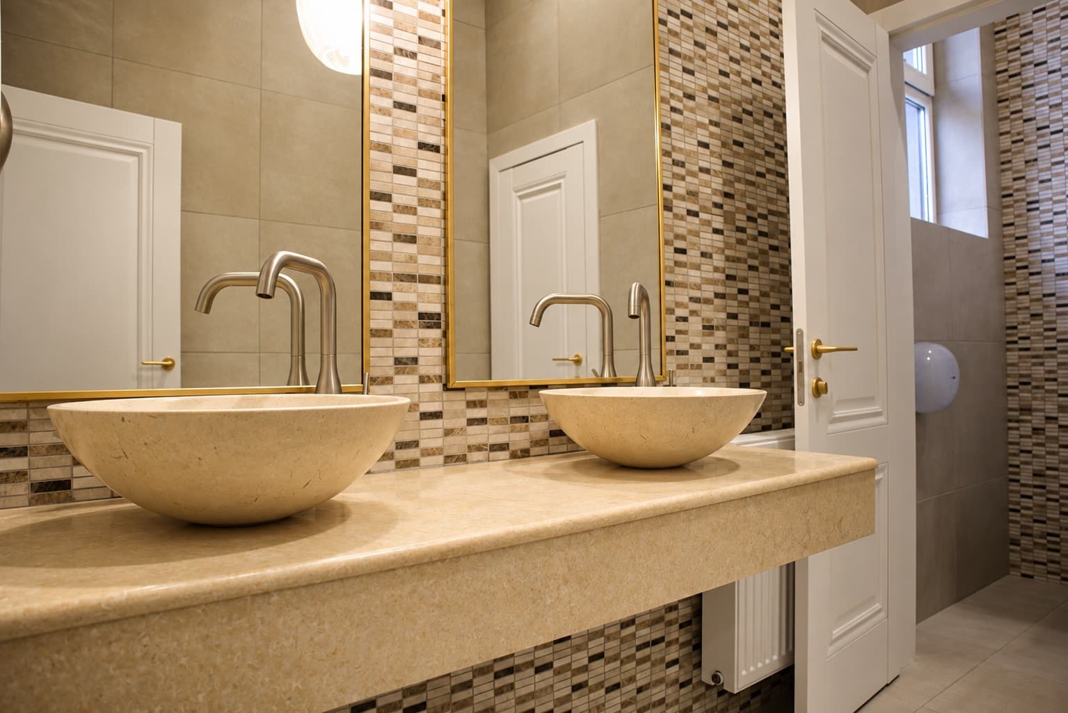 Round stone basins, a floating worktop and gold-framed mirrors