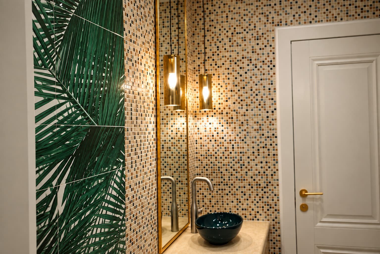 Green basin and floating worktop in a bathroom with mosaic tiles and a decorative botanical wall