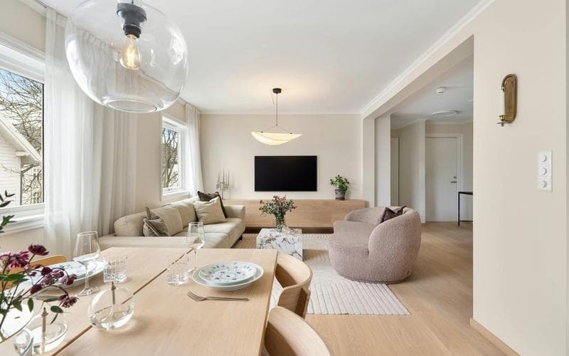 Living modern cu design interior minimalist, mobilier din lemn deschis, canapea crem și zonă de dining într-un spațiu luminos.
